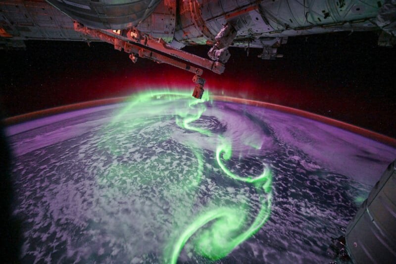 The aurora borealis seen from the International Space Station, glowing green and purple over Earth.
